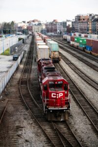 A red freight train with containers at a rail yard in Vancouver, showcasing industrial transportation.